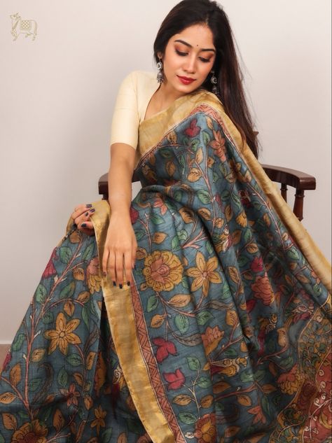 This rustic blue saree has Kalamkari work done all over the body and is paired with a Kalamkari pallu. #saree #traditional #weavesofindia #madeinindia #handcrafted #sareedraping #sareesofindia #sareelovers #handloomsofindia #indianwear #tussar #tussarsarees #chennai #sareeshopping #rasvriti Desinger Dresses, Unique Sarees, Painted Saree, Kalamkari Blouse, Tussar Saree, Kalamkari Sarees, Saree Traditional, Blouses Designs, Beautiful Sarees