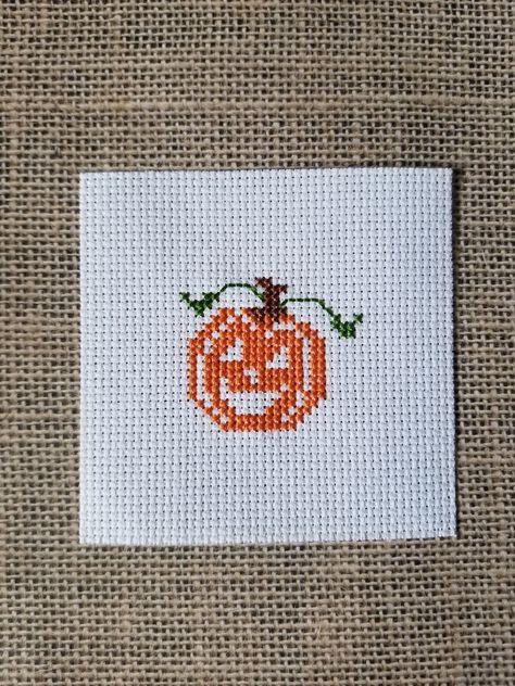 A happy pumpkin finished cross stitch piece.  It was stitched on white aida cloth which measures approximately 3.5" x 3.5".   It's ready to use in a variety of craft projects! Simple Halloween Cross Stitch, Miniature Cross Stitch Patterns Free, Small Halloween Cross Stitch Patterns, Mini Halloween Cross Stitch, Cross Stitch Sun, Cross Stitch Pumpkin, Cross Stitch Fall, Frog Cross Stitch, Cross Stitch Halloween