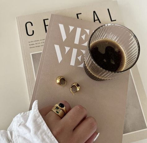 A girl is putting her hand on two tan colored books with a coffee cup on top and she’s wearing gold jewelry. Coffee And Jewelry Aesthetic, Coffee And Jewelry, Beige Pantone, Wood Living Room Decor, Gentle Aesthetic, Aesthetic Healthy Lifestyle, Jewellery Photography Inspiration, Jewelry Product Shots, Creative Jewelry Photography