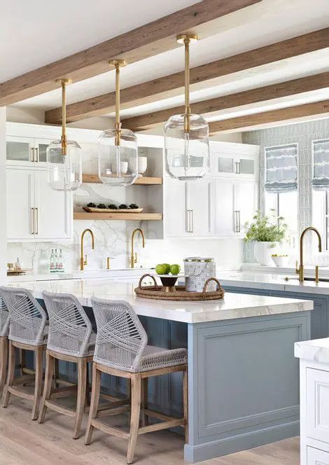 a fab coastal kitchen with white shaker style cabinets and a light blue kitchen island, glass pendant lamps and grey woven stools plus gold fixtures White Coastal Kitchen, Light Blue Kitchen, Coastal Inspired Kitchens, Coastal Kitchen Ideas, Blue Kitchen Designs, Blue Kitchen Island, Light Blue Kitchens, Stairs In Living Room, Blue Kitchen Cabinets