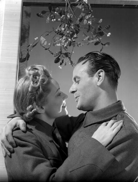 30th November 1939: An Auxiliary Fire Servicewoman and a British Army private kissing under the mistletoe. (Photo by Fox Photos/Getty Images) Why Do We Kiss, Kissing Under The Mistletoe, National Holiday Calendar, Christmas Couple Photos, Christmas Photograph, Fairytale Decor, Christmas Eve Traditions, Mistletoe Kiss, Vintage Kiss