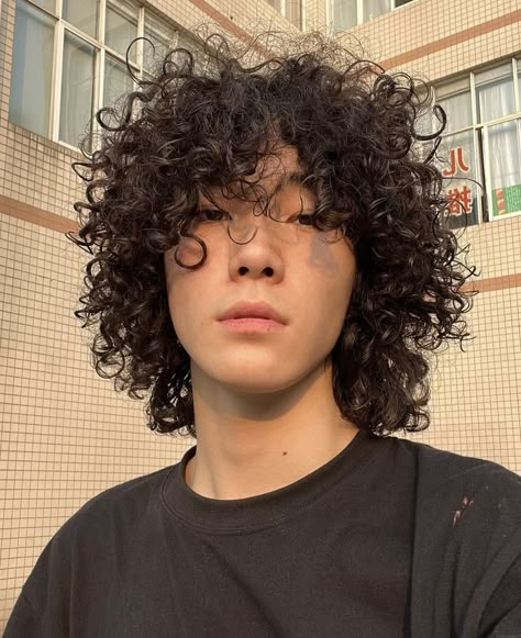 Asian boy with curly hair and a black top. The background is a checkered orange building with a few windows. Curly Hair Asian Guy, Asian Curly Hair Men, Asian With Curly Hair, Japanese Curly Hair, Jellyfish Haircut Men, Mixed Asian Men, Curly Hair Asian, Asian Curly Hair, Curly Asian Hair