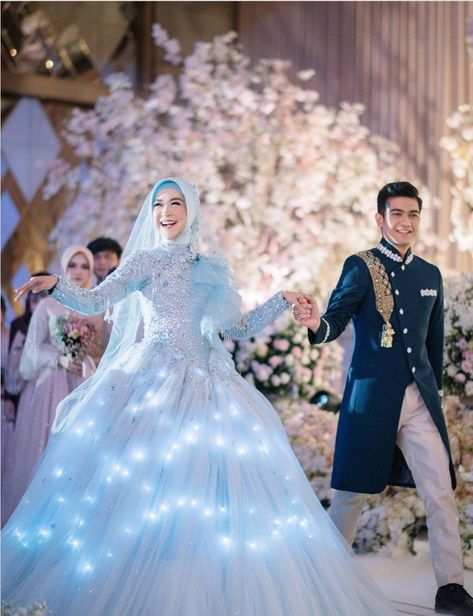 Ria Ricis tampil bak putri raja mengenakan ballgown yang dapat menyala. Gaya serupa juga pernah dipakai Rachel Vennya saat menikah dengan Niko Al Hakim. Rachel Vennya, Islamic Wedding Dress, Engagement Dress For Groom, Upacara Adat, Wedding Dress Hijab, Muslim Wedding Gown, Blue Wedding Gowns, Nikah Outfit, Dresses Hijab