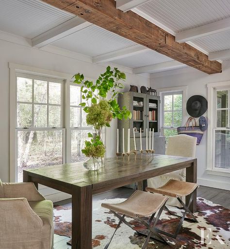 Cottage dining room featuring a dark brown wooden dining table joined with linen dining chairs and cowhide x stools. Cowhide Rug Dining, Cowhide Rug Dining Room, Dark Brown Dining Table, Brown Cowhide Rug, Bamboo Dining Chairs, French Dining Tables, Brown Dining Chairs, Cottage Dining Rooms, Modern Farmhouse Dining Room