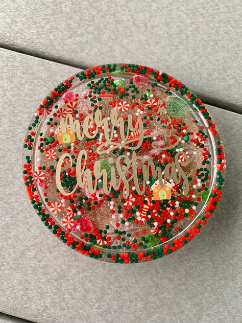 Merry Christmas decorative handmade coaster measures approximately 4 inches.  It is made with layers of resin.  Inside there is an assortment of holiday candies and sprinkles, the next layer is topped with a gold Merry Christmas logo. There is a cork bottom to protect surfaces or to prevent sliding. All patterns are one of a kind.  Handmade and May have slight imperfections.  Keep out of direct sunlight.  Do not clean with alcohol based products.   Not dishwasher or microwave safe.  Wipe with a Resin Christmas Gifts Diy, Christmas Epoxy Coasters, Christmas Resin Tray, Resin Christmas Coasters, Christmas Resin Art, Resin Christmas Ideas, Christmas Coasters Diy, Resin Christmas Ornaments Diy, Christmas Resin Coasters