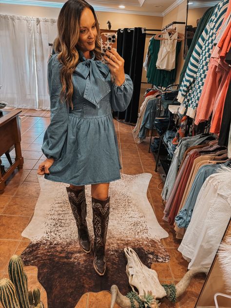 The prettiest denim dress with a front bow neck tie. Fits true to size. 80% Cotton, 20% Polyester Denim Dress With Cowboy Boots, Country Wedding Attire For Guests, Fall Denim Button-up Dress, Western Dress Outfits, Country Western Mini Dresses, Country Wedding Attire, Western Boutique Ranch Dress'n Western Boutique, Denim Dress With Cowbiy Boots, Chic Denim Mini Dress With Button-up Front