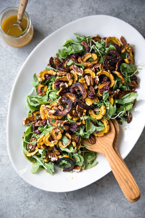 This green Thanksgiving salad recipe uses arugula, sweet roasted squash, pecans, cranberries and a apple cider vinaigrette. It's gluten-free, healthy, vegan, make-ahead and sure to rival any other side dish at your dinner table. | www.feedmephoebe.com Best Thanksgiving Salad, Squash Arugula Salad, Thanksgiving Dinner Sides, Thanksgiving Salad Recipes, Cider Vinaigrette, Arugula Salad Recipes, Thanksgiving Salad, Best Thanksgiving Side Dishes, Delicata Squash