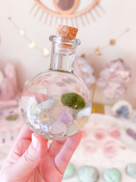 Embark on a magical journey with our DIY Crystal Fairy Water Garden, a mystical haven encapsulated within a captivating glass bottle. Immerse yourself in the enchantment of a live Marimo ball, a mini Amethyst sphere, and a symphony of Citrine, Prehnite, Rose Quartz, and Aquamarine chips, all harmonizing upon an aura-coated glass substrate. Awaken your inner sorceress as you infuse this ethereal garden with fresh distilled water upon arrival, and let the magic unfold. Monthly refreshes breathe ne Crystal Fairy, Notes Diy, Instagram Sales, Water Fairy, Amethyst Sphere, Crystal Garden, Diy Water, Bottle Corks, Angel Aura Quartz