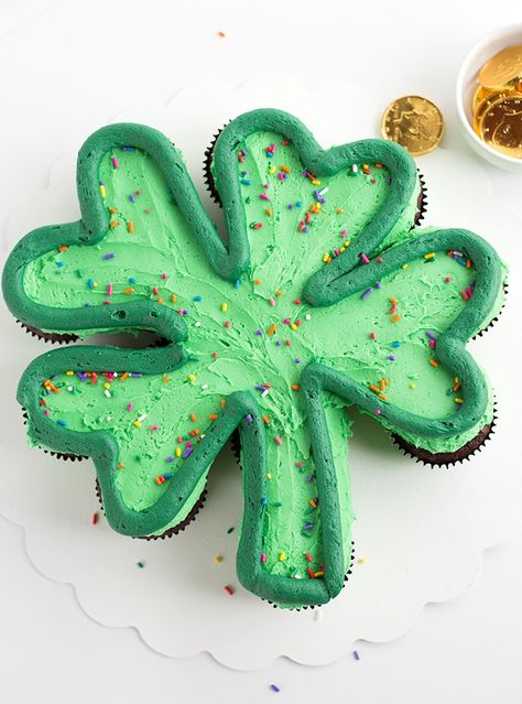 Green frosted cupcakes on a white cake board in the shape of a shamrock with a dark green outlining the shamrock and rainbow sprinkles on top Shamrock Cupcakes, Sprinkles Cupcakes, Pull Apart Cupcake Cake, Fete Saint Patrick, Pull Apart Cake, Cake Pulls, Pull Apart Cupcakes, St Patricks Day Food, Cupcakes Cake