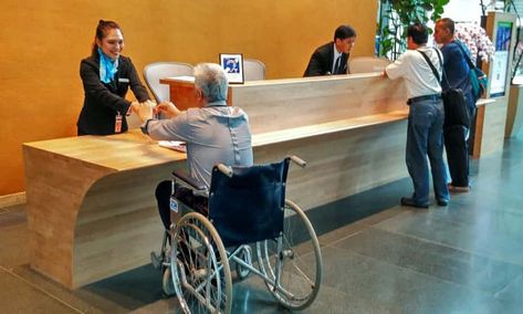 The reception area of the CapitaGreen building has a lowered front desk. The building has won numerous accessible design awards. Barrier Free Design, Hospital Reception, Front Desk Design, Reception Area Design, Accessibility Design, Desk For Office, مركز ثقافي, Reception Desk Design, Counter Desk