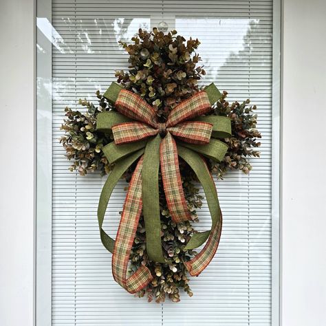 This beautiful handmade cross wreath is made with high-quality artificial eucalyptus foliage, which is densely packed to create a full and robust wreath. The wreath is designed with a wired ribbon bow placed in the center. The ribbon bow in the center is removable, and you can add ornamental adornments such as flowers, bows, and signage to the eucalyptus wreath base to suit your needs and the season you are decorating for. 📿MEASUREMENTS: The completed measurements for this wreath are approximately 25" H x 19" W x 4" D. It is a perfect size for front doors, entryways, and any indoor or outdoor wall decor. This wreath is assembled on a 20" x 13" plastic board constructed from 100% recycled plastic. It is weather, fade, and rust-resistant, making it durable and perfect for outdoor use. Due t Cross Wire Wreath Diy, Wreaths For Office Door, Cross Door Wreath, Cross Wreaths For Front Door, Church Entryway Decor, Burlap Cross Wreath, Cross Wreaths, Clothespin Cross, Cross Wreath Diy