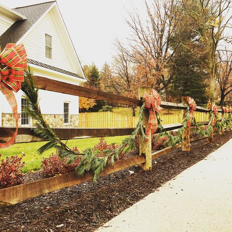 Fresh holiday garland on split rail fence Christmas Lights On Wood Fence, Christmas Split Rail Fence Decorations, Fence Garland Christmas, Garland On Fence Christmas, Split Rail Fence Christmas Decor, Garland On Fence, Christmas Fence Decor, Fence Christmas Decorating Ideas, Christmas Fence