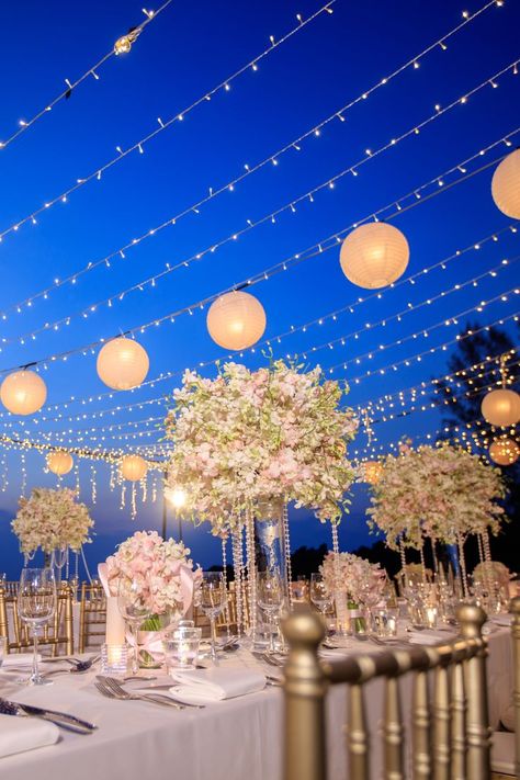 If you’re hosting an wedding, have fairy lights cascading overhead to give off a romantic vibe. Strings of fairy lights dangle from the canopy, transforming the space into a whimsical wonderland. Fairy Light Wedding Decor, Light Wedding Decor, Fairy Light Wedding, Navy Blue Wedding Decorations, Fairy Light Canopy, Fall Wedding Trends, Lanterns Wedding, Outdoor Wedding Lighting, Blue Wedding Decorations