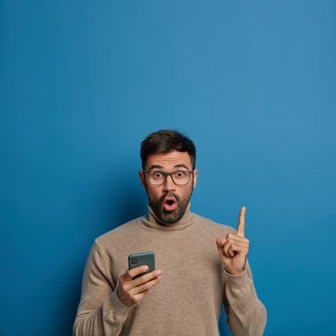 Surprised unshaven man holds phone, show... | Free Photo #Freepik #freephoto #man-smartphone #man-phone #amazed #pessoa-celular Man Holding Phone, Man Background, Man Pointing, Brown Jumper, Poppy Pods, Classy Suits, Vertical Images, Business Photoshoot, Mandala Vector