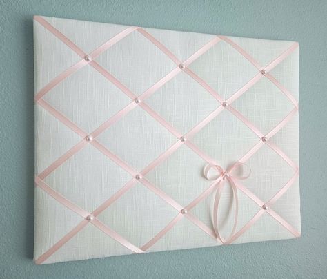 This delicate memo board in white linen fabric is accented with light pink satin ribbon and faux pearl details. Use it to display your photos, notes and cards, or just on its own as one of a kind soft wall hanging. Sizes: 20in wide x 16in tall (pictured) 24in wide x 18in tall 24in wide x 20in tall **Other sizes available, please contact me for details.** My memo boards and fabric pictures are carefully handcrafted using high quality materials, with generous batting. All my boards are light weigh Cork Board Covered In Fabric, Fabric Photo Board, Pink Walls Bedroom Ideas, Memo Board Diy, Pin Board Ideas, Pink Linen Fabric, Fabric Memo Boards, Cute Bulletin Boards, Pink Dorm