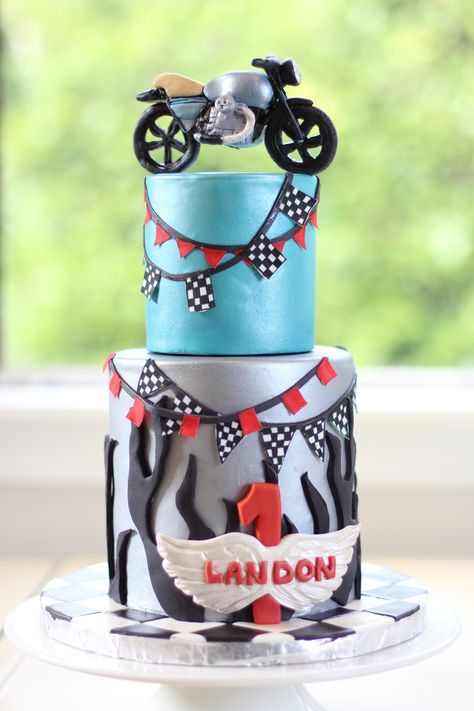 Motorcycle cake - Motorcycle first birthday cake. Fondant covered mini cake in 6 in and 4 in tiers. Modeling chocolate motorcycle, flames and name plaque.  Hand painted mini flags on sugar paper. Fondant checkered board. TFL  KO's Cakes :)   https://www.facebook.com/pages/KOs-Cakes/168270019865197 Motorbike Cake Kids, Grandpa Birthday Cake, Cake Motorcycle, Motorcycle Flames, Motorcycle Birthday Cakes, Motorbike Cake, Blaze Party, Bike Cake, Motorcycle Cake