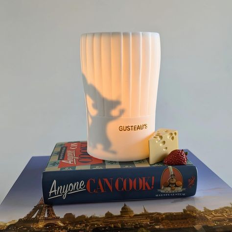 Remy is the highlight of the Ratatouille warmer, seated atop Gustaeu’s “Anyone Can Cook”. The Eiffel Tower is cut out of the back of the warmer and the image is cast when lit. Available only while supplies last! #scentsy #ratatouille #remy #anyonecancook #gusteau #wickedscents2 #waxwarmer #disney Gusteau Ratatouille, Scentsy Disney, Disney Ratatouille, Ratatouille Remy, Ratatouille Disney, Anyone Can Cook, Scentsy Buddy Clips, Scent Warmers, World Of Disney