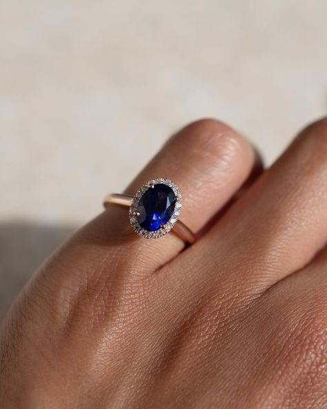 There’s something about that blue against the rose gold 💙 this regal engagement ring has a gorgeous blue sapphire centre, a bold halo, and a soft round profile rose gold band. Details: - 1ct oval blue sapphire - 18x round moissanites - 18k rose gold - 1.9mm wide shank #customengagementring #nz #aus #sapphireengagementring #bluesapphirering #bespokeengagementring Sapphire Engagement Ring With Band, Oval Blue Sapphire Ring, Oval Solitaire Sapphire Ring, Saphire Engament Ring Gold Band, Blue Sapphire Rings Engagement, Safire Rings, Regal Engagement Rings, Engament Rings, Coloured Gemstones