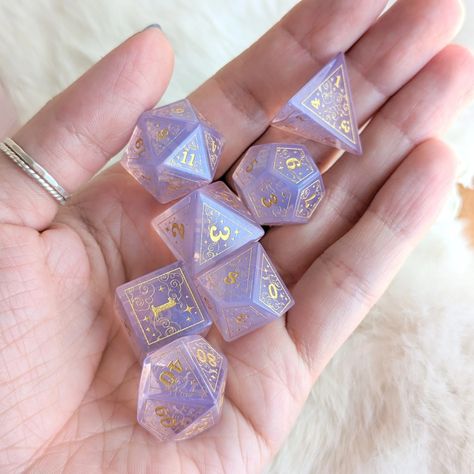 Introducing our latest addition to the collection - a stunning new dice set design featuring intricate swirling clouds, a crescent moon, and stars, all contained within a geometric border. These beautiful purple opalite dice are adorned with gold engravings that add a touch of elegance and magic to each die. We underst Purple Dnd Dice, Dice Sets Dnd, D&d Setup, D&d Gifts, Cute Dnd Dice, Dnd Dice Aesthetic, Dnd Magic Items, Dice Display, Mystery Aesthetic