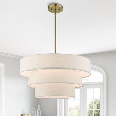 The pendant chandelier is both modern and versatile. The hand-crafted off-white colored fabric hardback shade is set off by the silky white fabric on the inside setting a pleasant mood. The triple drum shade adds character to this handsomely styled pendant. Perfect fit for the living room, dining room, kitchen, and bedroom. Base Finish: Antique Brass, Shade Color: Beige | Latitude Run® Samire 4 - Light Dimmable Drum Chandelier Textile / Metal in Yellow / Brown | Wayfair Fabric Drum Chandelier, Modern Organic Light Fixtures, Brass Chandelier Bedroom, Drum Chandelier Dining Room, Bedroom Chandelier Ideas, Light Fixtures For Low Ceilings, Vaulted Ceiling Lighting, Drum Shade Chandelier, Bedroom Chandelier