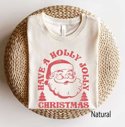 Retro Santa Tee, Santa Tee, Vintage Graphic Tee, Merry Christmas Shirt, Vintage Santa Graphic Tee, Classic Christmas Tee -- Graphic is distressed for a vintage vibe. SIZE UP for an OVERSIZED look (see size chart in listing photos). Looking for more Christmas and Winter themed apparel? Check these out: https://www.etsy.com/shop/TheGraphicPeach?ref=seller-platform-mcnav§ion_id=30496778 Our shop uses direct-to-garment printing to make our products. The design ink is sprayed on, then allowed to soak Winter Graphic Tees, Christmas Graphic Tees, Vintage Christmas Shirt, Santa Graphic, Retro Christmas Shirt, Santa Tee, Santa Sweatshirt, Retro Santa, Christmas Matching