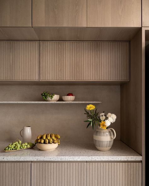 Tranquil Dreams - This kitchen features terrazzo quartz countertops and warm oak veneer panels with ribbed fronts, concealing a Pooja unit behind perforated shutters. A sand-colored vitrified tile backsplash complements the veneer, while concealed storage keeps the space sleek. Principal Designers - @saniya_jejani @loharsagar Design Team - @s1ddhant_ @pradnyxa @ar.saloni_jain Shot by - @nayansoni21 (Minimal interior design, modern interior design, minimalism, kitchen interior design, i... Terrazzo Quartz, Terrazzo Countertops, Minimalism Kitchen, Terrazzo Countertop, Pooja Unit, Earthy Palette, Minimal Interior, Minimal Interior Design, Concealed Storage