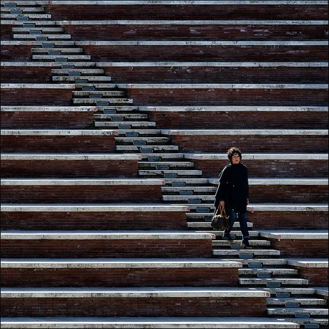 Element: Lines. This image showcases many different lines. There are both horizontal and diagonal lines and there is variation in the spaces between the two sets of horizontal lines. The woman in the corner stands draws attention in the image due to her lack of straight lines, making her the focal point. Line In Photography, Lines In Photography, Symmetry Photography, Photography Elements, Line Photography, Image Composition, Pattern Photography, Perspective Photography, Space Photography