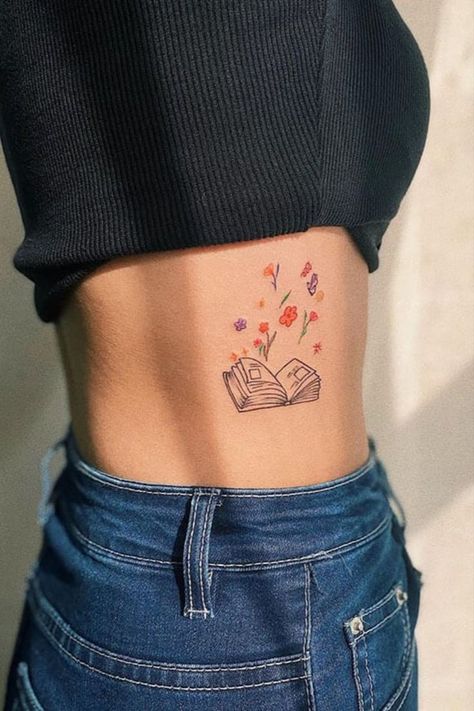 If you want to get a book tattoo, consider a small book tattoo with colorful flowers. This tattoo is located on the stomach and looks amazing. Book Tattoo Ideas For Women, Small Book Tattoo, Dainty Tats, Open Book Tattoo, Bookworm Tattoo, Book Tattoo Ideas, Book Inspired Tattoos, Reading Tattoo, Teacher Tattoos