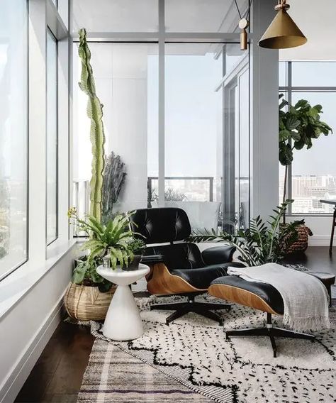 a chic nook with a black lounger and ottoman, a printed rug, potted greenery around is a very cozy space to read here Eames Chair Living Room, Black Eames Chair, White Scandinavian Living Room, Michael Hsu, Black Lounge Chair, Small Sunroom, Taupe Walls, Ball Chair, Lounge Chairs Living Room