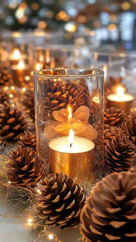 Festive table centerpiece featuring pine cone candles in glass vases, surrounded by gold pine cones and twinkling fairy lights. Cozy Christmas Bedroom Aesthetic, Cozy Candlelight, Indoor Christmas Decor, Large Pine Cones, Tall Glass Vases, Pine Cone Candles, Blue Christmas Decor, Christmas Table Decor, Industrial Style Decor