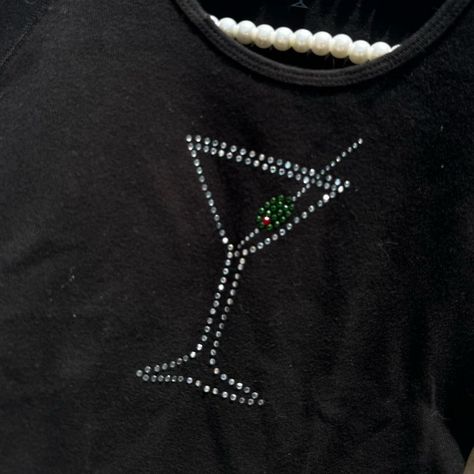 BLACK VINTAGE RHINESTONE STUDDED OLIVE MARTINI BABY TEE Super cute vintage black baby tee with a bedazzled rhinestone studded martini glass with an olive on the front In great condition Fabric is stretchy and soft! Size medium About 21” from top to bottom About 15” from pit to pit #vintage #retro #y2k #streetwear #90s #80s #babytee #tshirt #martini #olives #olive #club #clubbing #nightout #90sfashion #90saesthetic #y2kfashion #rhinestone #studded #sparkly #2000s #smallbusiness #explor... Rhinestone Graphic Tee, Olive Martini, Rhinestone Tshirts, Martini Olives, Spring T Shirts, 90’s Aesthetic, Streetwear 90s, Black Baby, 90s 80s