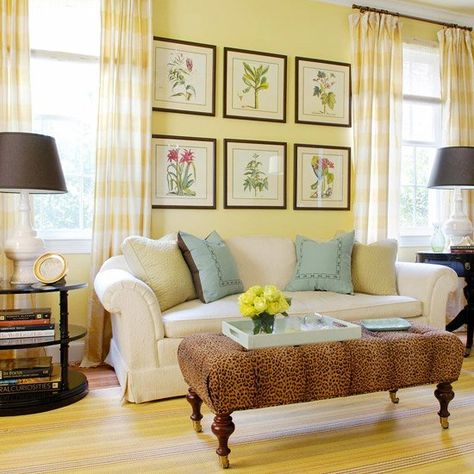 Light buttercream� yellow unites this large living room. It starts on the walls and echoes in the gingham curtains and the striped rug. The lighter yellow backdrop allows yellow wall decor and a lively animal print on the ottoman to take center stage. Adding black accents will give a yellow room more zing. Just be careful not to add so much black that you mimic the decorating equivalent of a bumblebee. Buttercream Walls, Living Room With Yellow Walls, Room With Yellow Walls, Yellow Living Room Colors, Pale Yellow Walls, Yellow Walls Living Room, Yellow Wall Decor, Yellow Room, Yellow Living Room