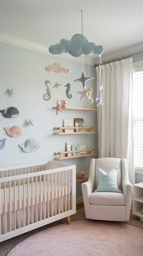 baby nursery in neutral ocean theme. cozy parent chair, white wooden crib, mobile with cloud and sea animals. Coastal Nursery Paint Colors, Unisex Ocean Nursery, 2 Under 2 Nursery, Sea Foam Nursery, Frozen Theme Nursery, Marine Life Nursery, Sea Life Nursery Theme, Seaside Nursery Theme, Beach Cottage Nursery