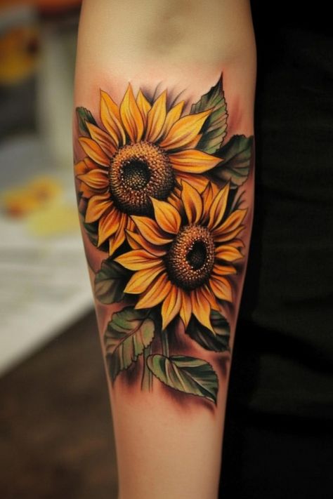 Two vibrant sunflowers tattooed on an arm with detailed leaves. Sunflower Tattoo Design Color, 3d Sunflower Tattoo, Tattoos With Sunflowers, Girasoles Tattoo, Color Flower Tattoo, Bold Watercolor, Sunflower Tattoo Ideas, Sunflower Tattoo Sleeve, Sunflower Tattoo Shoulder