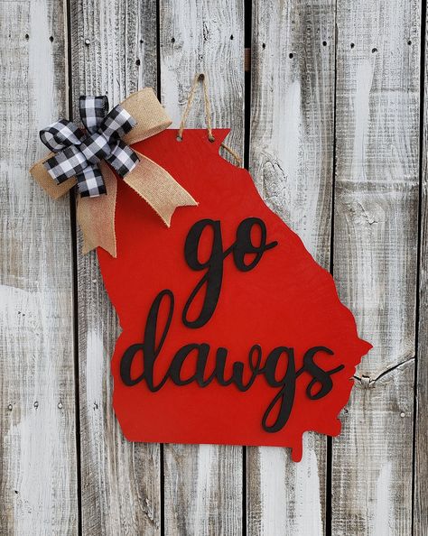 This adorable wooden door hanger or wall decor is perfect for the college fan in your life! It looks great on a door, porch, in an office, man cave, or bedroom. You can buy it unpainted and paint/design it yourself! It's very easy to DIY. Spray paint or craft paint the state and words and then use wood glue to attach the words. There are so many creative (yet easy) ways you can finish these differently even from my pictures. If you order it painted it will come painted like the pictures or in th Alabama Door Hanger, Wooden Football, Football Door Hangers, Go Dawgs, Monogram Door Hanger, Wooden Things, State Of Georgia, Diy Spray Paint, Office Man