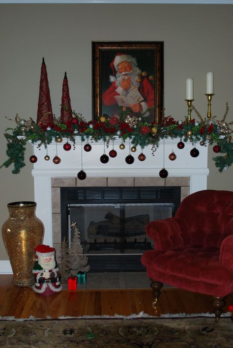 Our Christmas Mantle like the ornaments not the Santa pic Christmas Fireplace Baubles, Red And Green Mantle Decorations, Christmas Mantel With Santa Picture, Santa Mantle Decor, Garland With Hanging Ornaments, Christmas Mantle Wreath, Mantle Decorating Ideas For Christmas, Santa Mantle, Christmas Mantle Ideas