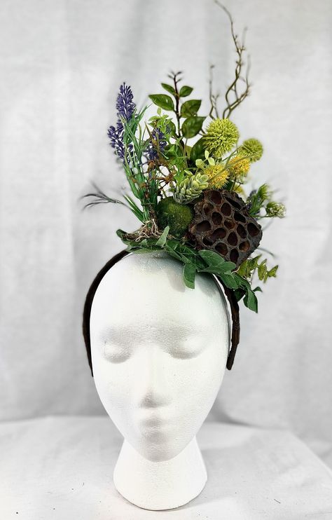 "A fascinator headpiece mounted on a headband for extra ease and support, this piece was inspired by the lush green foliage of the Pacific Northwest. Featuring a natural dried Lilly pod focal point, with purple, yellow and white faux wildflowers tucked amongst moss, a pinecone and various green foliage mounted on a brown ribbon-wrapped headband.  Measures approximately 15\" in height from the bottom of the headband to the top of the tallest point, and about 9\" in width." Insect Headpiece, Floral Fascinators, Floral Headdress, Flower Costume, Nature Goddess, Fairy Festival, Green Accessories, Flower Fascinator, Floral Hat