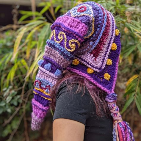 I like to add all sorts of details to the tassels of my hoods. This one has a sterling silver moon, glass beads, an electroformed amethyst, and lovely silver and gold tube beads. I also braided in hand dyed hemp fabric and hand spun wool, strips of velvet, and tiny braids incorporated as well. Pattern: Fae Elf Hood by @earthtricks #crochet #faeelfhood #handmade #crochethood #warlock #festivalfashion #slowfashion Fae Crochet Pattern, Fairy Hat Crochet, Green Whimsical Crochet Yarn Hat, Crochet Elf Hood, Bohemian Purple Crochet Hat, Tiny Braids, Crochet Fantasy Hood, Freeform Crochet Earthfaire, Moon Glass