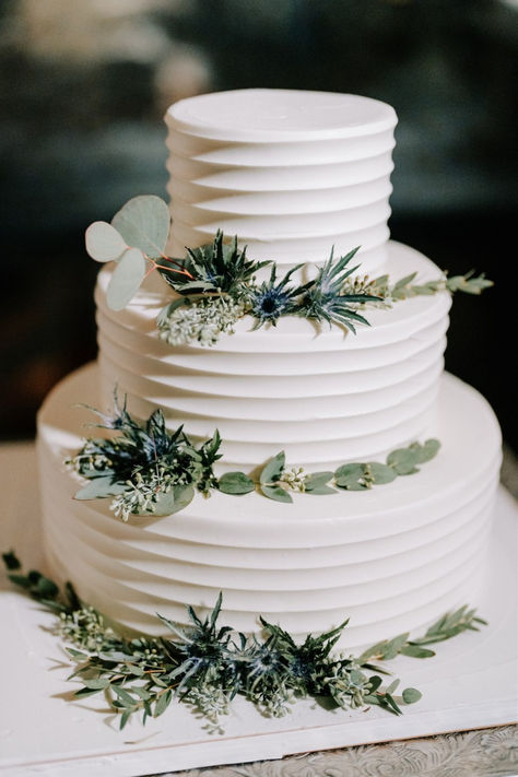 Simple yet stunning, this three-tiered white wedding cake adorned with fresh eucalyptus leaves exudes natural elegance. Perfect for couples seeking a chic, modern design with a touch of greenery for their wedding day. The eucalyptus adds a subtle, organic vibe to this timeless cake.  Photo: Longbrook Photography Wedding Cake Leaves, Wedding Cake Forest Green, Minimalist Wedding Cake Rustic, Wedding Cake With Sage Green, Wedding Cakes Simple Elegant Modern, Green Wedding Cake Ideas, Wedding Cake Sage Green, Forest Green Wedding Cakes, Wedding Cake With Eucalyptus