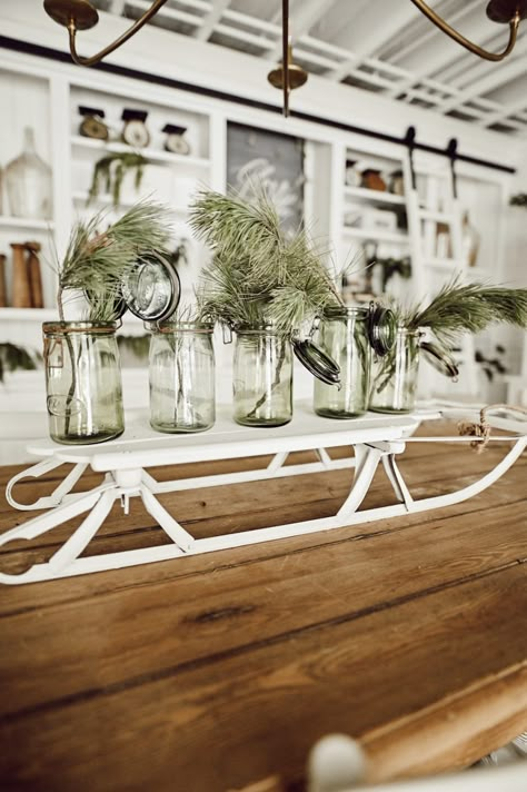 White sled centerpiece with green jars. #wintergreens #centerpiece #wintercenterpiece #greenjars #vintage Diy Sled, Christmas Sleigh Centerpiece, Sleigh Decorations, Sled Decor, Affordable Christmas Decorations, Vintage Sled, Christmas Sled, Liz Marie, Winter Centerpieces