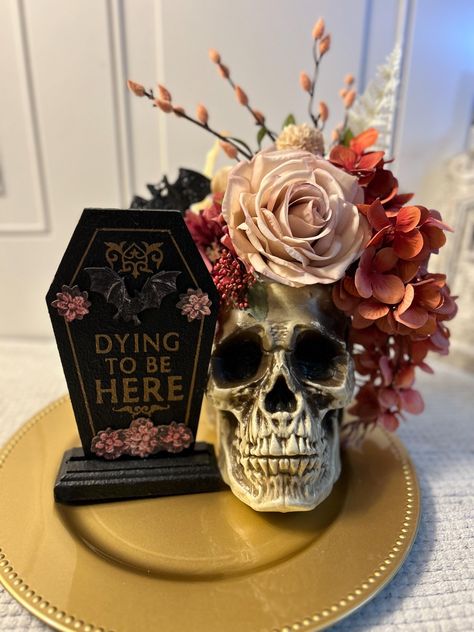 Skull floral arrangement. Pink, black and gold with a gorgeous skull centerpiece. Beautiful and elegant centerpiece. A unique hand painted coffin shaped sign will  add a small shabby chic gothic touch to any room. This skull and floral centerpiece is a perfect Halloween decoration, or Halloween wedding decor for that extra special touch. Totally shabby chic. Sizing/Dimensions 13 inches wide and 19 inches tall Features: Lightweight Durable  Gold base  Black, pink, white flowers This is the actual Gothic Candelabra Centerpiece, Spooky Table Centerpieces, Gothic Party Centerpieces, Glam Skull Decor, Goth Baby Shower Games, Gothic Wedding Party Favors, Witchy Centerpieces Wedding, 30th Birthday Rip 20s, Gothic Wedding Centerpieces Table Decor