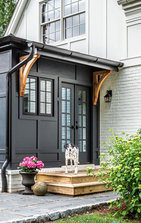 This board and batten exterior is contrasting in it's black and white tones. Subtle hints of wood and brick bring in more charm. + black exterior + modern exterior + residential exterior + back patio design + exterior lighting + board and batten exterior | Terracotta Design Build Co. Wide Board And Batten Exterior, Board And Batten Siding With Black Windows, Brick And Panel House Exterior, Taupe Board And Batten Exterior, Brick With Board And Batten Exterior, Brick And Black Exterior, Board And Batten Siding With Brick, Black Board And Batten Exterior, Brick And Batten