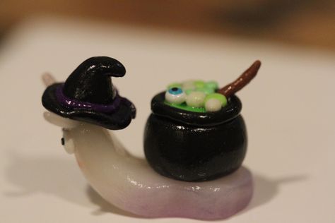 Handmade clay snail with cauldron on back. Snail has a purple hue on the bottom done with chalk pastel. The cauldron is bubbling over with green and glow in the dark stew and it seems an eye ball has risen to the top of the stew. Snail also features a witch hat. All pieces are handmade and my differ slightly from the picture. Mini Halloween Clay Ideas, Halloween Clay Figures, Spooky Clay Ideas, Goth Clay Ideas, Clay Slugs, Clay Cute Ideas, Cute Clay Stuff, Little Clay Ideas, Clay Halloween Crafts