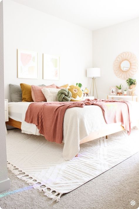 My favorite bedroom styling to date 🥰 loving the bright pinks, yellows, and greens. So summery! White Bedding With Pop Of Color, White Bedding Ideas Pop Of Color Pink, Pink And Wicker Bedroom, Pink Green Cream Bedroom, White Orange Pink Bedroom, Pink Yellow White Green Bedroom, Neutral Bedroom With Yellow Accent, Sage Green Pink And Mustard Bedroom, Pink Bed Styling