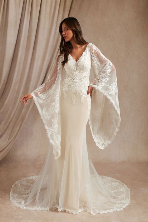 Walk down the aisle effortlessly with our tulle and lace mermaid gown, Harmonia. Her V-neckline is adorned with hand sewn lace that drapes over your shoulders and onto the illusion scoop back. Her billowy angel sleeves are trimmed with our eyelash lace. Her figure-hugging skirt extends to a chapel train that is adorned with a lace motif. Loose Lace Wedding Dress, Wedding Dress With Wing Sleeves, Romantic Wedding Dress Flowy Sleeves, Long Bell Sleeve Wedding Dress, Boho Flare Sleeve Wedding Dress, Witchy White Wedding Dress, Bellsleeve Wedding Dress, Wedding Dress Dramatic Sleeves, Boho Wedding Dress Lace Vintage Hippie Bell Sleeves