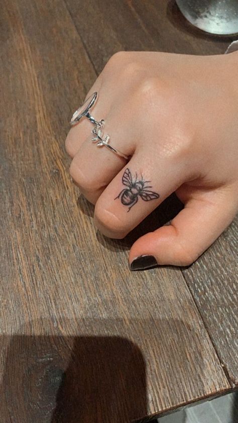 Bee Tattoo Finger Ideas, Bee On Finger Tattoo, Honey Bee Hand Tattoo, Finger Tattoos Bee, Hand Bee Tattoo, Cowrie Shell Tattoo Design, Small Floral Tattoo Designs For Women, Bumble Bee Finger Tattoo, Finger Bee Tattoo