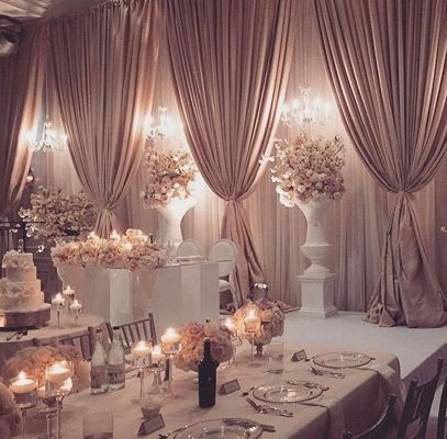 Double draped walls with chandeliers, pedestals and floral arrangements Tied Curtains, Wedding Reception Head Table, Reception Head Table, Wedding Reception Hall, Fitness Shirts, Bride Magazine, Hall Decor, Wedding Elegant, Wedding Hall