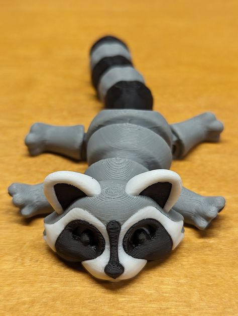 These Raccons are Extra chunky   Extra chunky and extra fun!!  Get yours now while you still can!! This 3D Printed Articulating Raccoon is a perfect addition to your home decor. With its unique design, this fun desk companion is sure to bring a smile to your face every time you see it. This raccoon figurine is made with high-quality 3D printing technology, ensuring its durability and longevity. Key Features: - Unique 3D printed design - Articulating joints for added fun - High-quality printing f 3d Printing Ideas Cute, 3d Print Animals, 3d Printed Animals, Raccoon Figurine, Cool 3d Prints, 3d Printing Ideas, 3d Printing Toys, 3d Tiskárna, Fun Desk