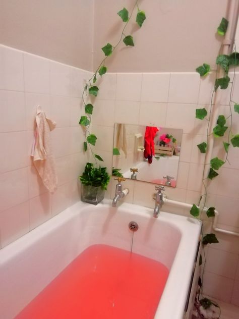 Hanging wall vines in green features a glass vase with fake flowers inside and a bath after bath bombs Vines Decor, Wall Vines, Fake Vines, Bathtub Photography, After Bath, Hanging Wall, Fake Flowers, Corner Bathtub, Alcove Bathtub