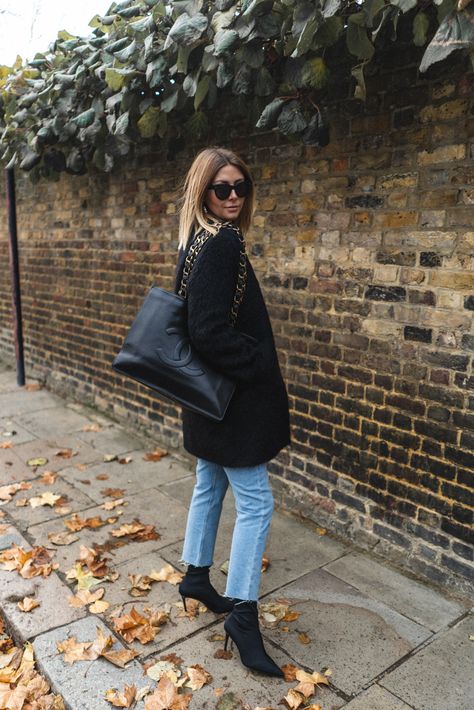 Emma Hill wears Black coat, Vintage Chanel tote bag, bleach wash raw hem jeans, black sock boots, chic Autumn Fall Winter outfit Black Sock Boots Outfit, Deauville Chanel, Canvas Outfit, Tote Bag Chanel, Sock Boots Outfit, Black Sock Boots, Tote Bag Outfit, Chanel Tote Bag, Chanel Outfit